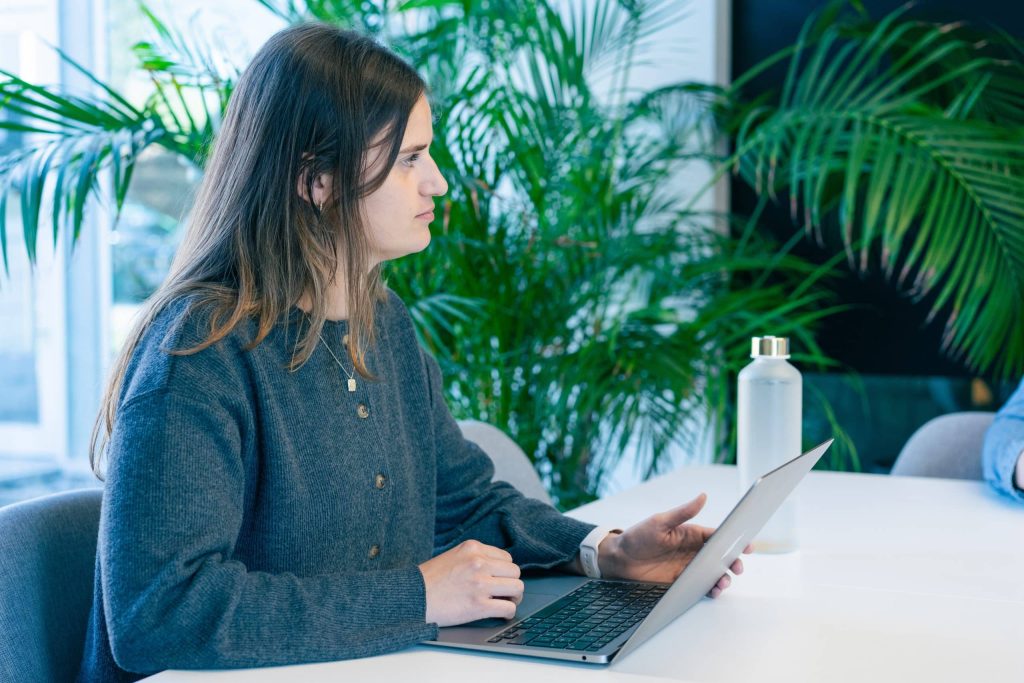 GEO-expert werkt op een laptop tijdens een overleg in een groene kantooromgeving