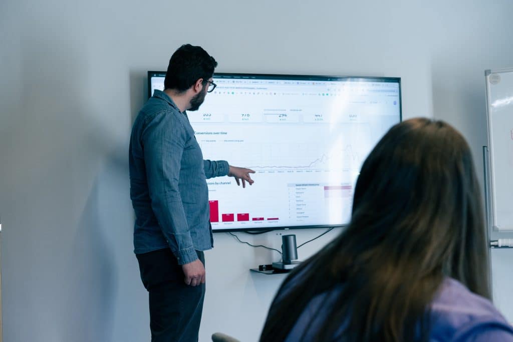 Marketeer van een online marketingbureau presenteert groeidata op een groot scherm