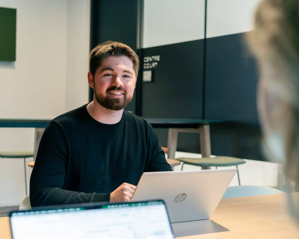 SEA-specialist in overleg in een SEA agency terwijl hij achter zijn laptop werkt