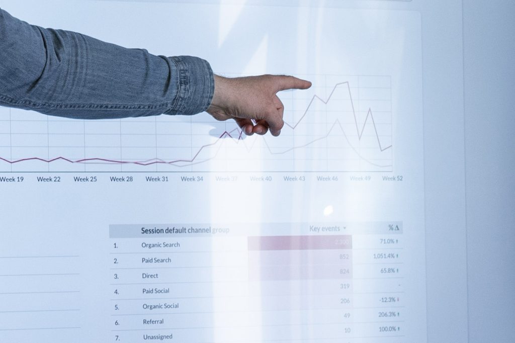 Een persoon wijst naar stijgende websitecijfers op een scherm tijdens een rapportage door een SEO agency