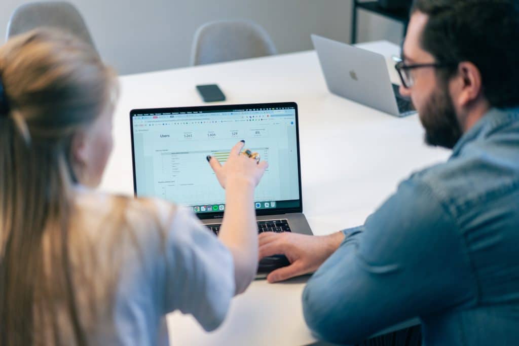 Twee medewerkers van een online marketingbureau analyseren website­statistieken op een laptop