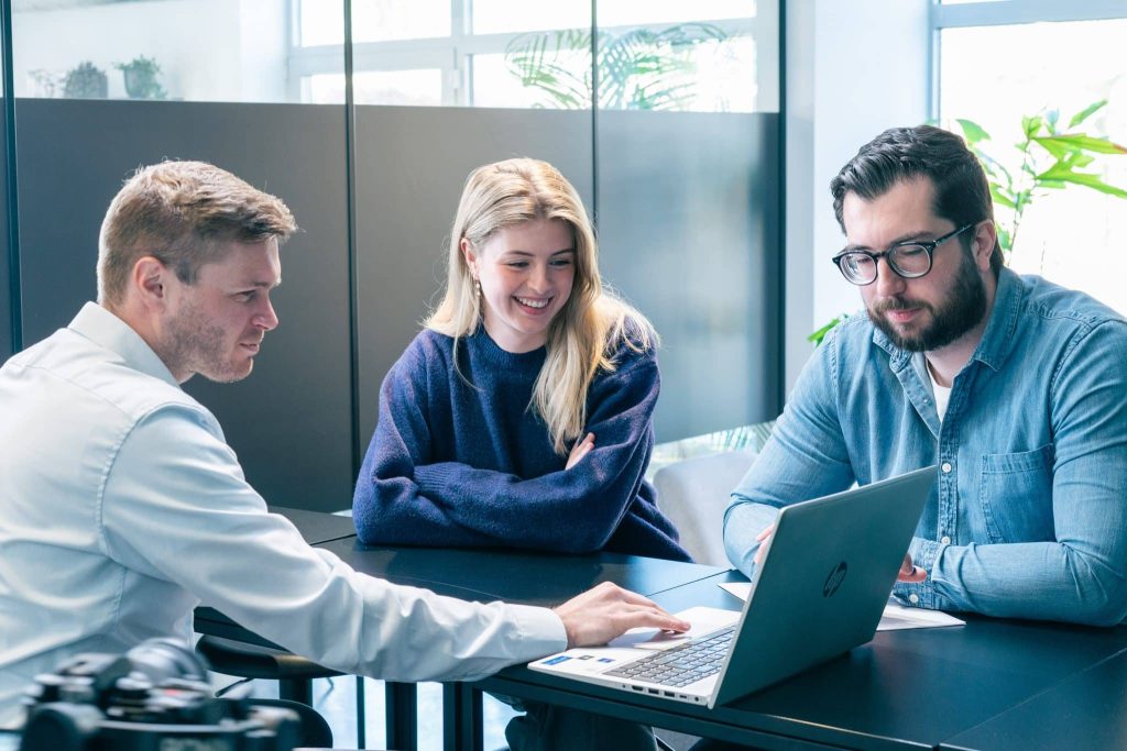 Team bespreekt online marketingstrategie rond een laptop in een vergaderruimte