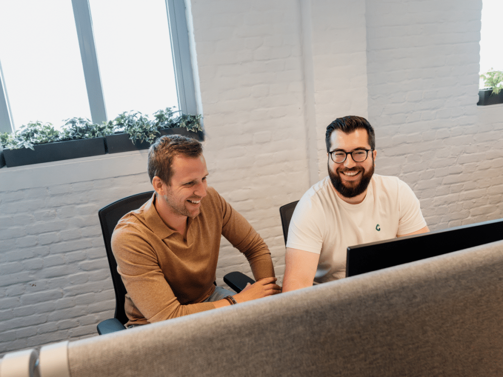 Yordi en Maxime bekijken samen Google Ads resultaten op een scherm op kantoor