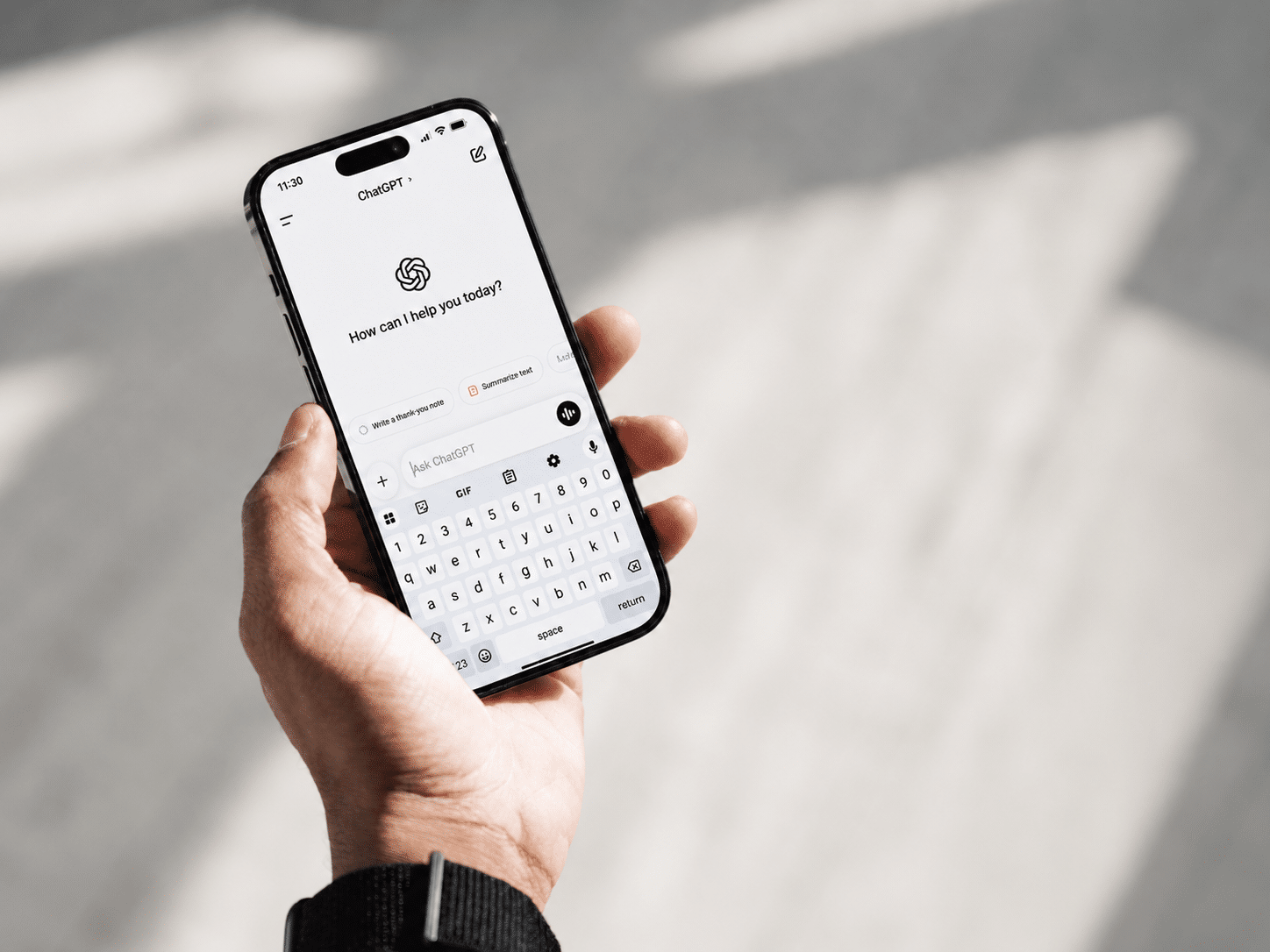 Hand houdt een smartphone vast met de ChatGPT-app open, klaar om een vraag in te typen.