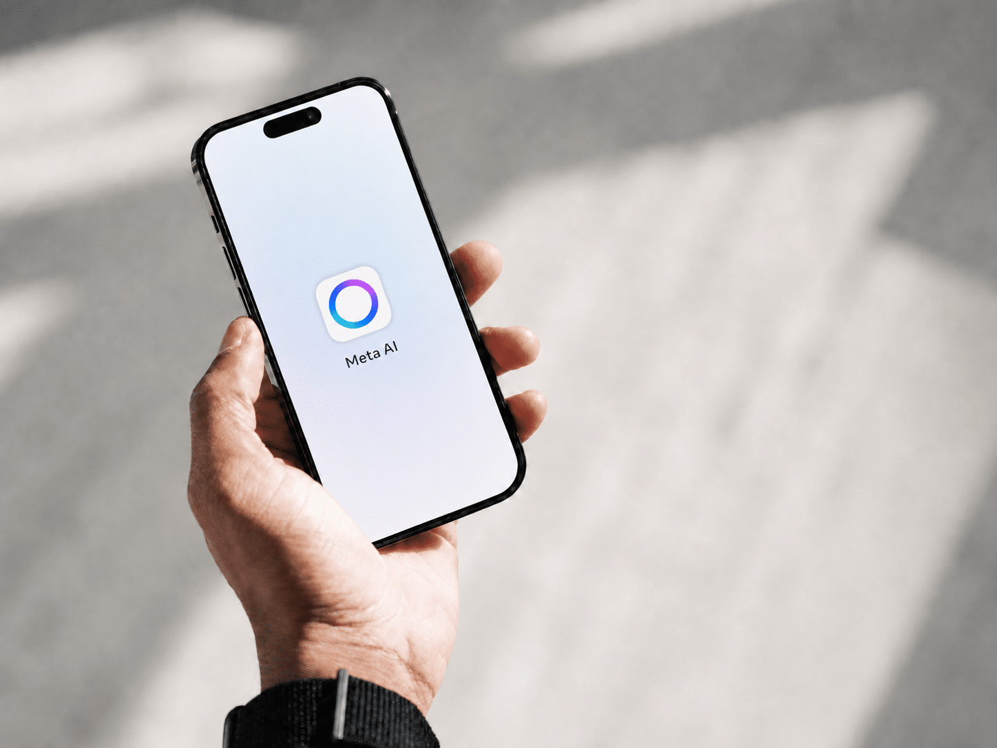 Hand houdt smartphone vast met de Meta AI-app op het scherm, symbool voor hoe Meta's AI de controle over advertentietargeting overneemt.