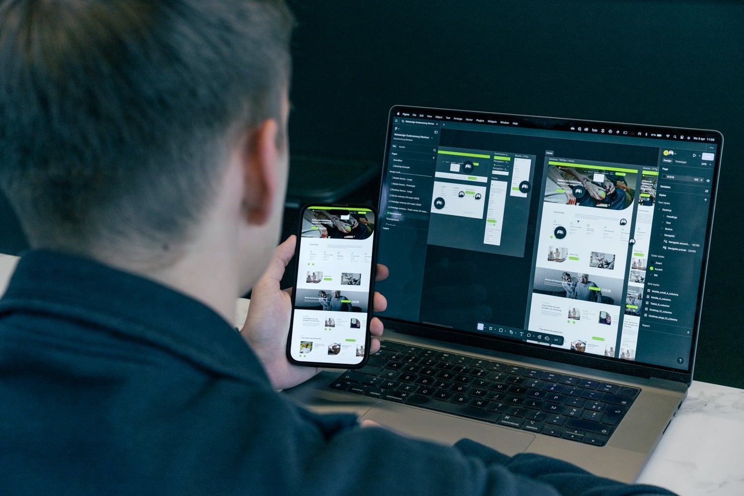 Designer vergelijkt een website-ontwerp in Figma op laptop en smartphone, als voorbeeld van testen op verschillende schermformaten.