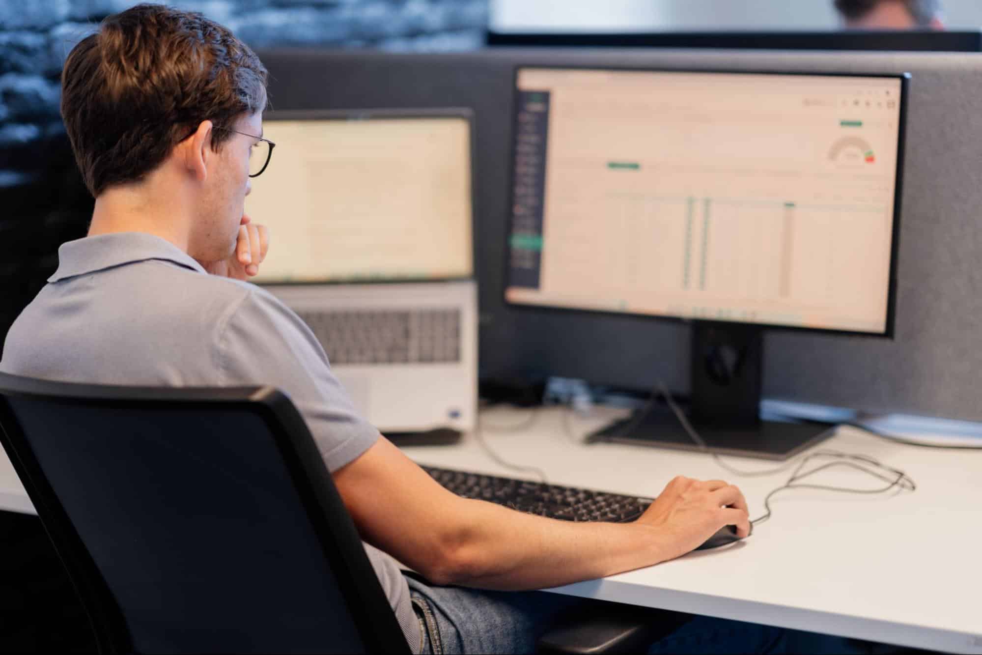Conversal-medewerker analyseert bedrijfsdata op twee schermen tijdens het opzetten van een datagedreven workflow.