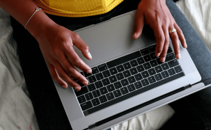 Close-up van handen op een laptoptoetsenbord, iemand bekijkt een website met een header video